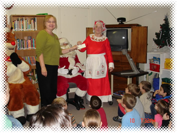 Friends President Terry Slone presents Mrs. Santa a generous check with Santa and Rudolph watching on